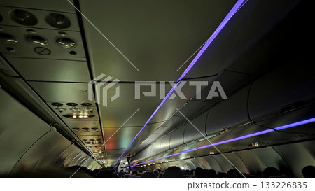 Commercial aircraft interior with colorful ambient lighting in flight 133226835