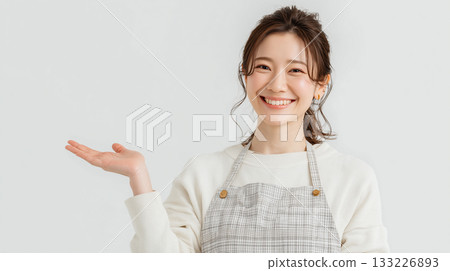 A woman in a checked apron greets with a smile 133226893
