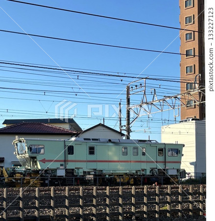 A bright green maintenance vehicle parked along an urban railway line 133227123