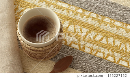 Unity Cup Rests on a Woven Mat Beside a Wooden Spoon in a Cozy Setting 133227132