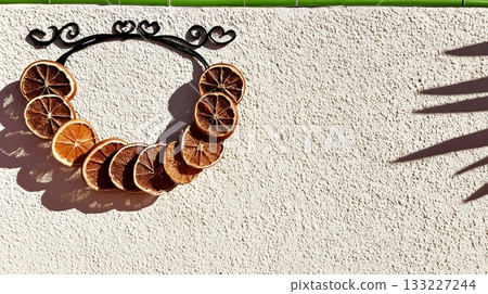 Dried Orange and Cinnamon Wreath Hangs on a Textured Wall in Soft Afternoon Light Dried Orange and Cinnamon Wreath Hangs on a Textured Wall in Soft Afternoon Light 133227244