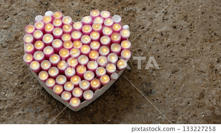 Heart Shape Made of Tiny Candles Glowing Softly on a Neutral Surface During Evening Hours 133227258