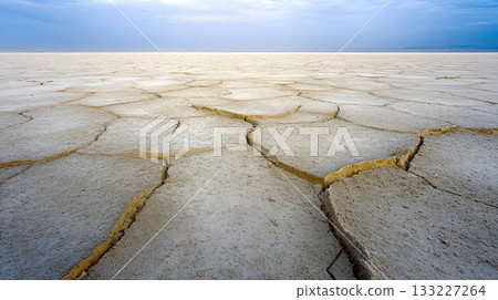 Dry, Cracked Earth Under Extreme Heat in an Arid Landscape With Blue Sky at the Horizon 133227264