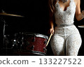 Female drummer performing on stage with vibrant red drum set 133227522