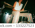 Female drummer performing energetically on stage with colorful outfit 133227523