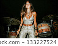 Female drummer performing passionately on stage with vibrant energy 133227524