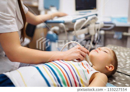 Doctor conducts ultrasound examination of heart, abdominal organs of little boy using equipment. 133227554