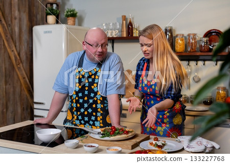 White couple planning recipe together at counter, chopping board with vegetables, smartphone recipe reference, focused discussion, shared meal prep, cozy domestic White couple planning recipe together at counter, chopping board with vegetables, smartphone recipe reference, focused discussion, shared meal prep, cozy domestic 133227768