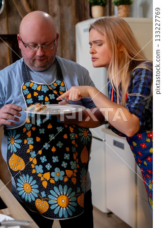 White couple grating cheese for pasta, man using grater while woman holds bowl, cherry tomatoes on wooden board, utensils and relaxed weekend cooking vibe, warm kitchen White couple grating cheese for pasta, man using grater while woman holds bowl, cherry tomatoes on wooden board, utensils and relaxed weekend cooking vibe, warm kitchen 133227769