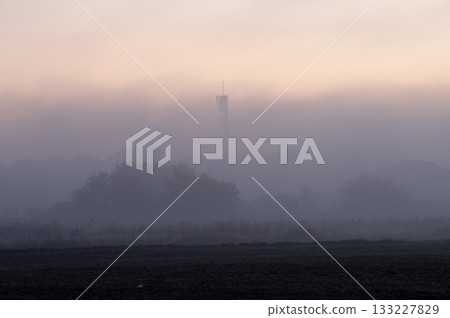 田野籠罩在晨霧中，一座無線電塔漂浮在蒼白的天空中。 133227829
