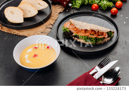 Healthy flatbread sandwich with lettuce and tomato, creamy soup, restaurant setting Healthy flatbread sandwich with lettuce and tomato, creamy soup, restaurant setting 133228173