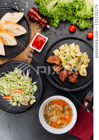 Hearty restaurant lunch: soup, fried meat with potatoes, fresh cabbage salad and bread 133228174