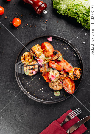 Colorful grilled vegetables with char marks on black plate, close-up, healthy vegetarian dish Colorful grilled vegetables with char marks on black plate, close-up, healthy vegetarian dish 133228175