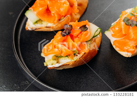 Gourmet salmon canapes on baguette with cream cheese and cucumber on black plate Gourmet salmon canapes on baguette with cream cheese and cucumber on black plate 133228181