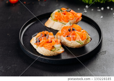 Gourmet salmon canapes on baguette with cream cheese and cucumber on black plate Gourmet salmon canapes on baguette with cream cheese and cucumber on black plate 133228185