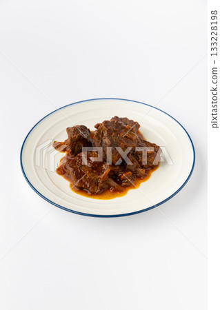 Beef stew chunks in rich tomato sauce on white plate, studio food shot 133228198
