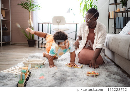Mother and toddler playing with toys on living room floor 133228732