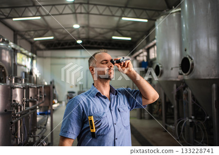 Brewer performing quality control with refractometer in brewery Brewer performing quality control with refractometer in brewery 133228741