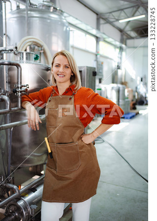 Female brewer smiling in a modern craft beer brewery 133228745