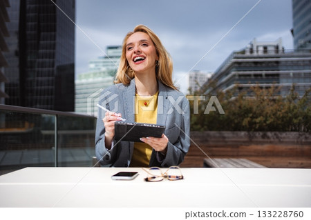 Businesswoman laughing, enjoying tablet technology during a break Businesswoman laughing, enjoying tablet technology during a break 133228760