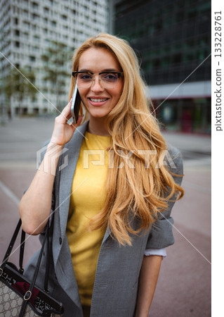Stylish young businesswoman talking on phone in city street 133228761