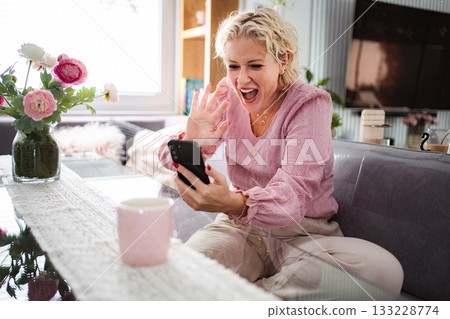 Happy woman waving during video call on smartphone Happy woman waving during video call on smartphone 133228774
