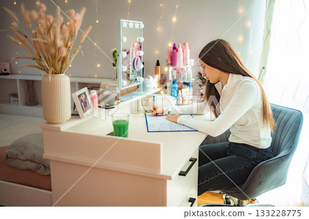 Young woman concentrating on writing assignments at home desk 133228775