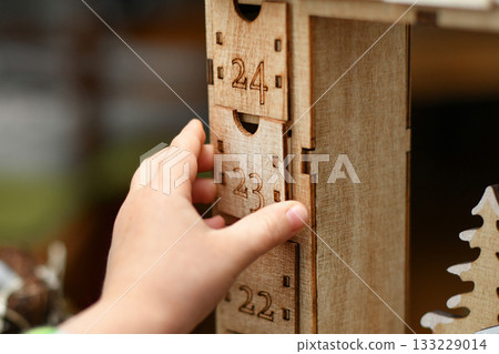 A child opens wooden advent calendar with presents 133229014
