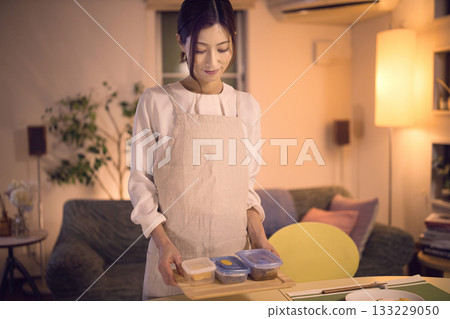 中年婦女端著晚餐走向餐桌。 133229050