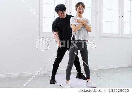 Young woman receiving training from a personal trainer 133229060
