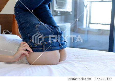 一位女士穿著牛仔褲躺在床上,臀部線條優美,展現了她苗條的身材和健康的體態。 一位女士穿著牛仔褲躺在床上,臀部線條優美,展現了她苗條的身材和健康的體態。 133229152