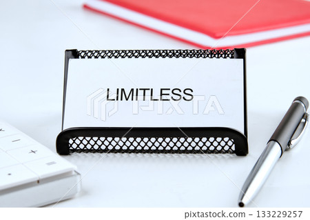 A card displaying the word LIMITLESS lies on a neat desk surrounded by a pen and a keyboard. Bright red notes in the background suggest organization and focus on goals A card displaying the word LIMITLESS lies on a neat desk surrounded by a pen and a keyboard. Bright red notes in the background suggest organization and focus on goals 133229257
