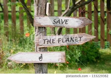 Three wooden arrow signs are attached to a weathered tree trunk. The signs read SAVE THE PLANET and one has a pointing finger, all encouraging action for environmental preservation 133229362