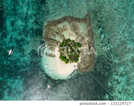 Small tropical island with palm trees sandy beach and boats in turquoise water near coral reef. Guyam Island. Siargao, Philippines. Small tropical island with palm trees sandy beach and boats in turquoise water near coral reef. Guyam Island. Siargao, Philippines. 133229727