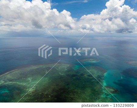 Turquoise sea with visible coral reef formations stretching toward horizon under blue sky. Siargao, Philippines. 133229809