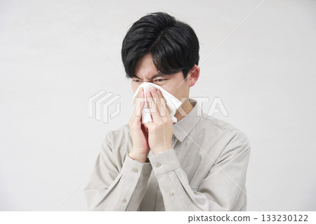 Man blowing his nose, 20s, white background Man blowing his nose, 20s, white background 133230122