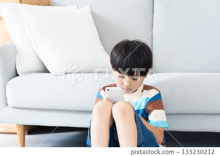 小學生在客廳玩智慧型手機 133230212