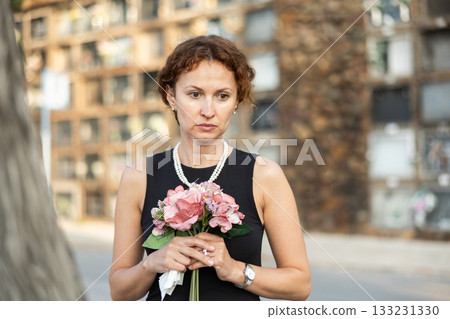Woman brought flowers to the cemetery and cries over the death of beloved relative 133231330