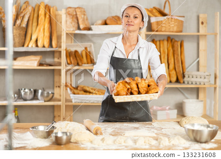 A bakery worker shows off a variety of different crescent-shaped buns. 133231608