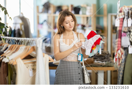 Glad young girl choosing panties in clothing store 133231610