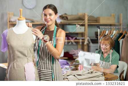 Young woman working with mannequin, elderly woman sewing 133231621