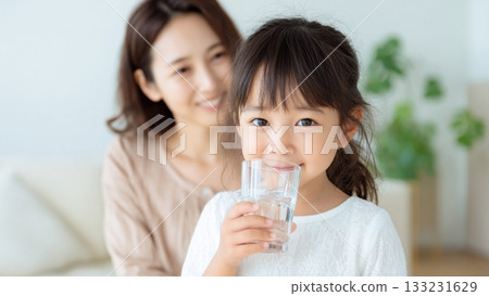 Girl and mother drinking water from a glass 133231629