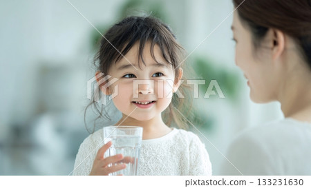 Girl and mother drinking water from a glass 133231630