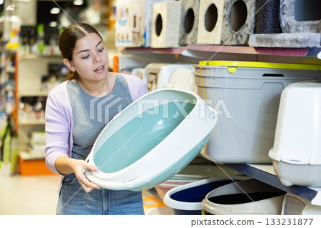 Young woman choosing plastic litterbox for cats in pet shop 133231877