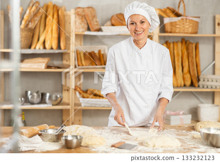 Professional female baker preparing pizza dough in bakery Professional female baker preparing pizza dough in bakery 133232123
