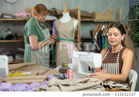 Female seamstress working on a typewriter against the background of a dressmaker and a mannequin Female seamstress working on a typewriter against the background of a dressmaker and a mannequin 133232137