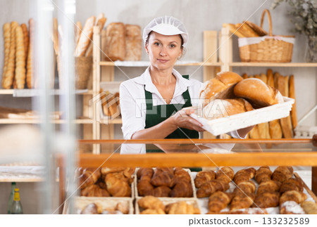 Female baker worker sells loafs of breads Female baker worker sells loafs of breads 133232589