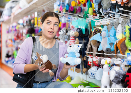 Young cheerful woman buying toys for pets in pet store 133232590
