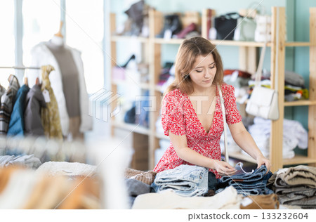 Young woman choosing jeans in clothing store 133232604