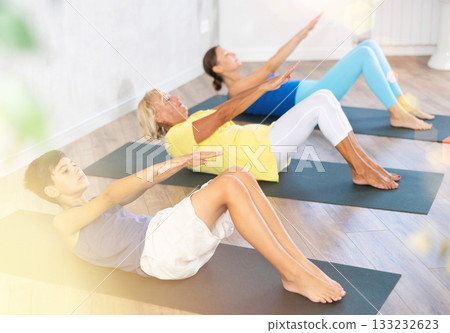Mom, grandmother and teen grandson performing exercises to strengthen press, pump muscles of core 133232623